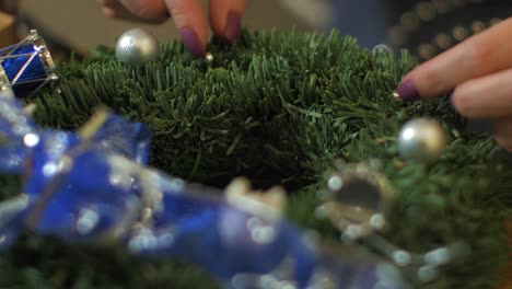 Woman-making-a-fir-Advent-wreath-for-Christmas-Eve-and-decorating-it-with-silver-pearls,-diy-craft-decoration,-winter-traditions,-seasonal-holidays,-hands-close-up-shot