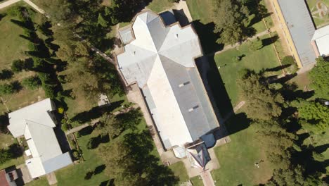 Top-down-orbital-rising-of-a-romantic-architectural-style-church-surrounded-by-trees,-Santa-Anita,-Entre-Rios,-Argentina