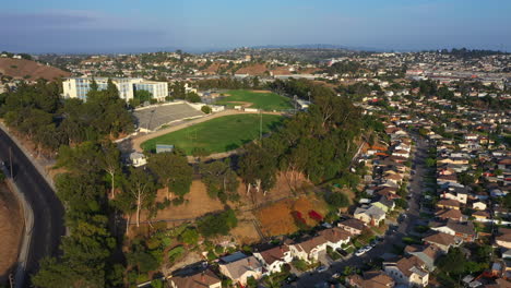 Flug-über-Die-Wunderschöne-Vorortstadt-Los-Angeles-In-Richtung-Einer-Epischen-Highschool-Mit-Grünem-Fußballfeld