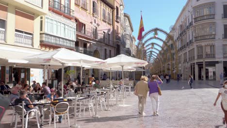 Menschen-In-Masken-Spazieren-An-Einem-Sonnigen-Tag-In-Malaga,-Spanien,-Mit-Der-Wunderschönen-Calle-Marques-De-Larios-Im-Hintergrund-–-Weitwinkelaufnahme