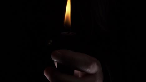 Hands-around-a-candle-at-vigil-close-up-shot-on-dark-background