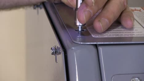 Tightening-screws-on-exterior-metal-plating-of-paint-mixer-machine-with-a-socket-power-drill-close-up