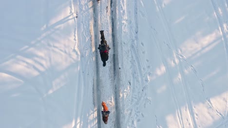 Luftaufnahme-Von-Oben-Auf-Jockeys,-Die-In-Einer-Verschneiten-Winterlandschaft-Reiten
