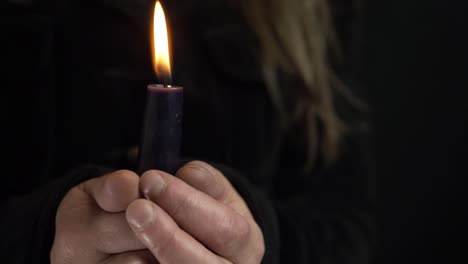 Woman-holding-a-long-candle-for-vigil-on-dark-background-medium-shot