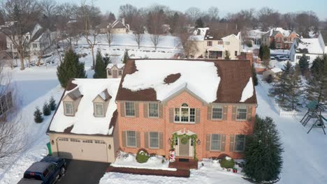 Descending-aerial-of-red-brick-home-decorated-with-holiday-garland