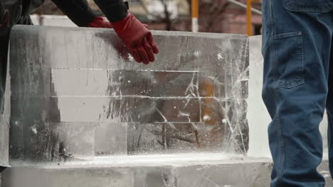 Ice-sculptor-sliding-block-of-ice-into-position-to-carve,-Slow-Motion