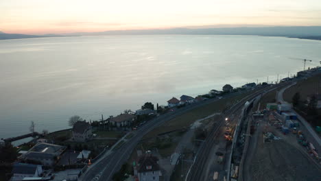 Aerial-of-small-town-under-construction-near-large-lake-at-sunset