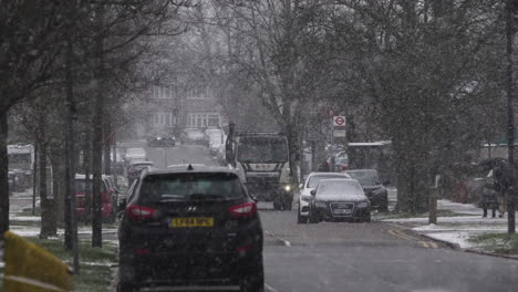 Cars-And-Skip-Lorry-Driving-Past-On-Residential-Road-In-Snow