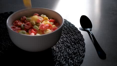 Froot-loops-cereal-being-poured-into-bowl-of-milk,-slow-motion