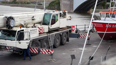 Hydraulic-crane-vehicle-lifting-fishing-boat-on-Conwy-welsh-harbour