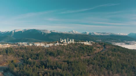 Aerial-view-of-Simon-Fraser-University-on-a-hill-and-mountains-on-background-in-British-Columbia,-Canada