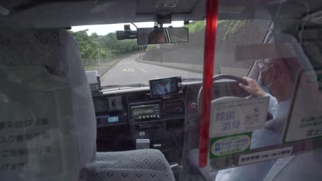 Taxi-Driver-Wearing-Face-Mask-While-Driving-On-The-Road-With-Plastic-Barrier-Installed-During-Pandemic-In-Shizuoka,-Japan