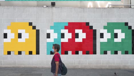 Menschen-Werden-Gesehen,-Wie-Sie-An-Einem-Wall-Street-Kunstwerk-Vorbeigehen,-Das-Das-Klassische-Arcade-Spiel-Pac-Man-In-Hongkong-Darstellt