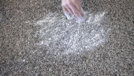 Verteilen-Sie-Brotmehl-Auf-Einer-Arbeitsplatte-Aus-Granit,-Während-Sie-Sich-Darauf-Vorbereiten,-Hausgemachte-Sauerteig-Bagels-Zu-Kneten-Und-Zu-Kochen