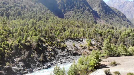 Turistas-Cruzando-El-Puente-Colgante-Sobre-El-Río-Marshyangdi-En-El-Circuito-De-Annapurna,-Nepal