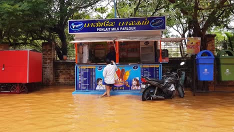 Ein-Indischer-Mann-Versucht,-Etwas-Milch-In-Einem-Ponlait-Milchladen-Mitten-Auf-Einer-überfluteten-Straße-In-Pondicherry-Zu-Kaufen
