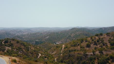 Vista-Aérea-Que-Muestra-La-Cordillera-Verde-Y-La-Carretera-Asfaltada-En-El-Borde-Durante-El-Viaje-De-Verano-En-Algarve,-Portugal
