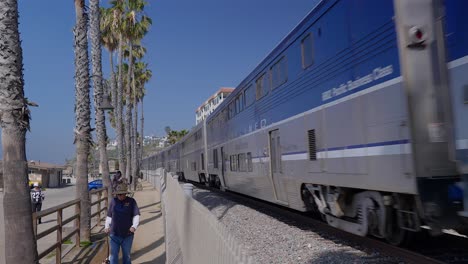 Pacific-Surfliner-train-running-through-San-Clemente-next-to-a-guy-walking-his-dog