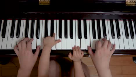 Toddler-playing-piano-with-adult,-four-hands,-piano-duet