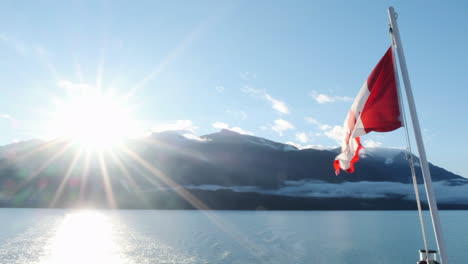 Canada-flag-on-BC-ferry-with-spectral-sunrise-sun-ball-over-mountain