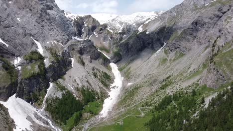 Drohnenflug-Durch-Ein-Grünes-Tal-Mit-Etwas-Schnee-In-Der-Schweiz
