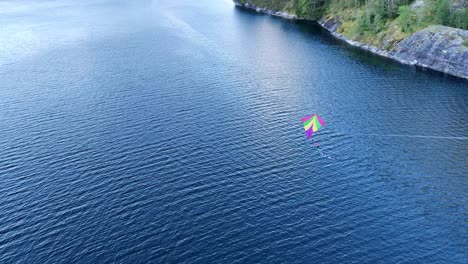 Colorful-toy-kite-blowing-in-the-wind---Outdoor-children-activity---Handheld-tiltup-of-kite-blowing-in-the-wind-above-Norwegian-fjord