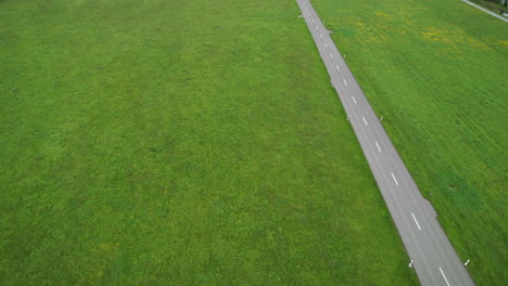 Lonely-electric-car-drives-on-road-across-green-meadow
