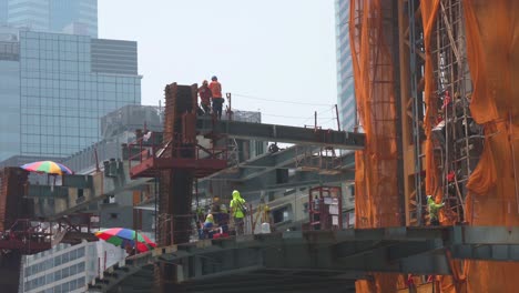 Während-Im-Finanzdistrikt-Hongkongs-Bauarbeiten-Im-Gange-Sind,-Sieht-Man-Bauarbeiter,-Die-Eifrig-An-Einer-Stahlkonstruktion-Im-Stadtentwicklungsprojekt-Arbeiten