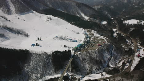 Vista-Aérea-De-La-Estación-De-Esquí-Cubierta-De-Nieve-En-Un-Soleado-Día-De-Invierno-En-Okuhida-Hirayu,-Gifu,-Japón