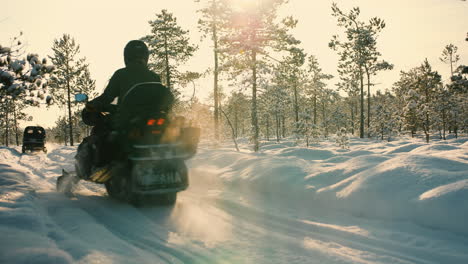 Snowmobiles-from-behind-on-a-sunny-winterday-in-a-snowy-forest