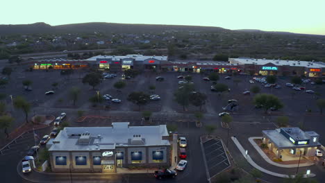Drone-View-Of-Cars-Lined-Up-Outside-A-Fastfood-Chain-In-Green-Valley-At-Dusk