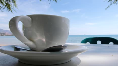 Eine-Tasse-Kaffee-An-Einem-Tisch-Im-Freien-Am-Strand-Mit-Blick-Auf-Das-Meer-Auf-Einer-Tropischen-Insel-In-Timor-Leste,-Südostasien