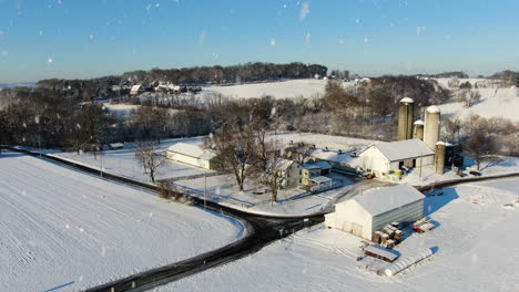 AERIAL-Orbital-Around-Farm-Buildings-On-Snowing-Winters-Day