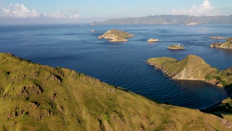 Padar-island-southern-tip-with-Komodo-isle-in-the-distance-in-Indonesia,-Aerial-pan-right-reveal-shot