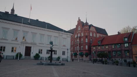 Main-Square-Stortorget-in-Centre-of-Ystad-With-Person-Walking-In-Front-Of-Store-Thor,-South-Sweden-Skåne,-Wide-Shot-Tracking-Sideways-from-Right-To-Left