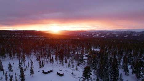 Cabins-and-winter-forest-landscape-in-a-burning-sunset