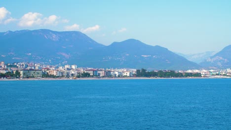 View-of-Alanya-city-from-the-sea,-sunny-summer-day,-wide-handheld-shot-from-a-boat