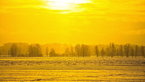 Blick-Auf-Den-Sonnenuntergang-Im-Zeitraffer-über-Schneebedeckten-Landwirtschaftlichen-Feldern-Mit-Autos,-Die-In-Der-Ferne-Die-Autobahn-Entlangfahren