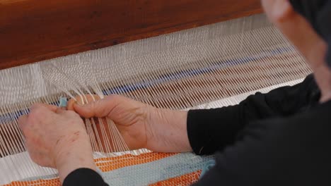 Over-the-shoulder-view-of-an-old-lady-weaving-a-rug-on-a-traditional-loom