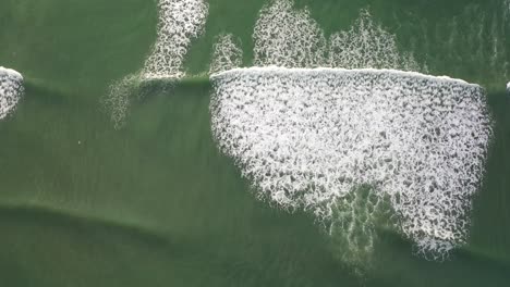 Unique-top-down-drone-shot-of-waves-crashing-on-beach