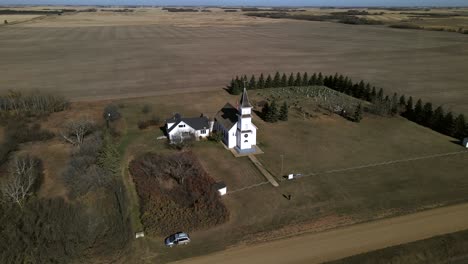 Drone-Orbitando-Alrededor-De-La-Hermosa-Iglesia-Del-País-Antiguo-En-Las-Praderas-De-Alberta-Mientras-Desciende-Lentamente-Y-Se-Acerca-Al-Edificio-De-Madera
