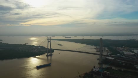 drone-view-of-Ship-moving-towards-large-modern-suspension-bridge-in-early-morning-light