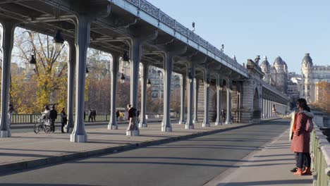 Bir-hakeim-bridge-with-people-taking-pictures-and-walking-during-golden-hour-in-Paris,-pannig-wide-shot
