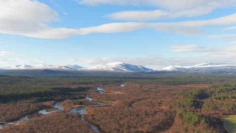 Parallax-Drone-Shot-Of-Snowcapped-Swedish-Mountains-Surrounded-By-Alpine-Forest-And-River