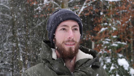 Man-getting-hit-by-snowball-to-his-head-while-wearing-hat-during-snowfall,-close-up-view