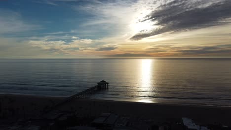 Luftaufnahme-über-Den-Manhattan-Beach-Pier,-Kalifornien,-Mit-Wellen,-Die-Bei-Sonnenuntergang-An-Der-Sandigen-Küste-Krachen