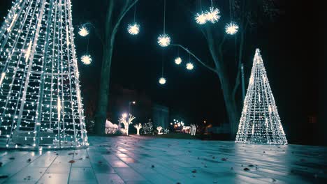 Filmische-Vorwärts-Steadicam-Aufnahme-Im-Low-Modus-Der-Weihnachtsbeleuchtung-In-Der-Nacht,-Einige-Lichter-Hingen-In-Den-Bäumen-Und-Gefälschte-Weiße-Kiefern-Mit-LED-Lichtern