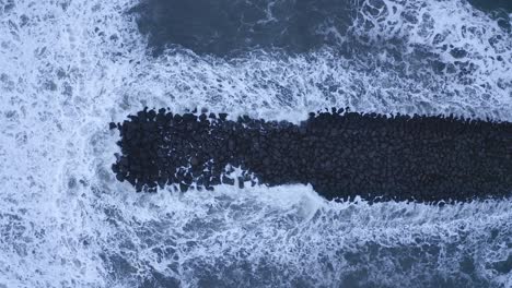 Giant-Waves-overflooding-black-basalt-rocks-on-Vi-kurfjara-Beach,Iceland,aerial-top-down