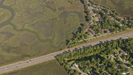 Savannah-Georgia-Aerial-v49-vertical-birds-eye-view-overlooking-at-traffic-crossing-on-highway-away-from-the-neighborhood-at-whitemarsh-island-surrounded-by-beautiful-natural-marshland---October-2020
