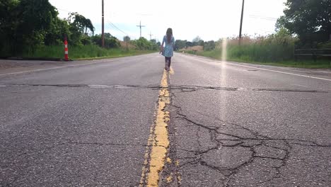 Little-Girl-Walking-On-The-Yellow-Line-Dividing-Lanes-Of-Asphalt-Road-With-Cracks